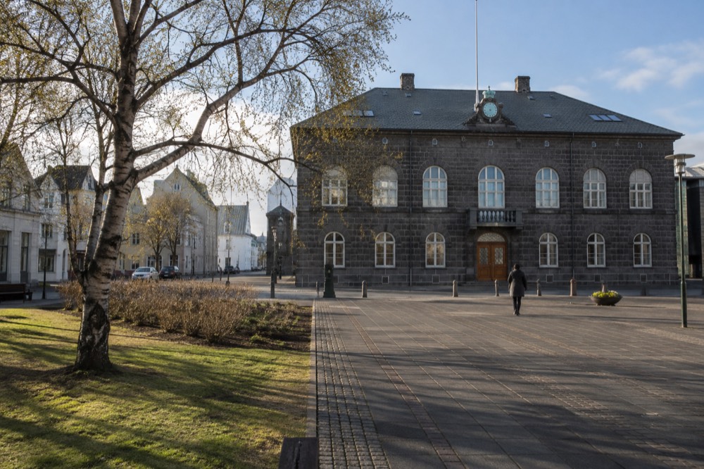 A stone square in front of a classical parliament building in Reykjavik