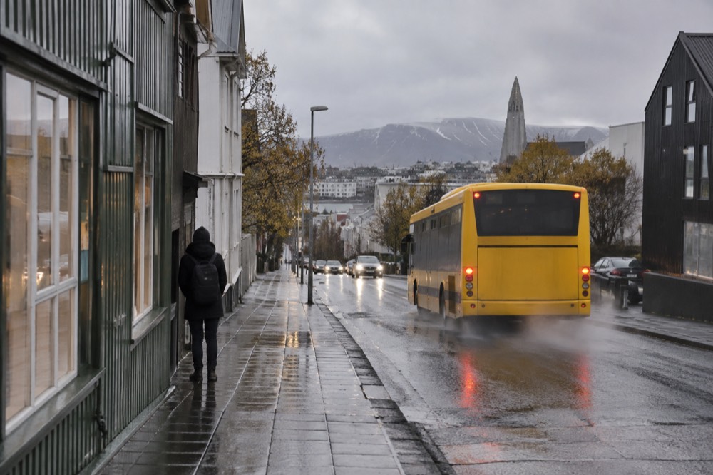 A city bus pulling away from a stop on a Reykjavik street