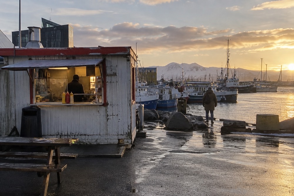 Hot dog stand by the old harbour with small boats moored behind