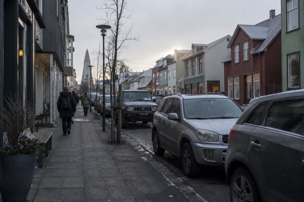 Parking meters and parked cars along a Reykjavik storefront street
