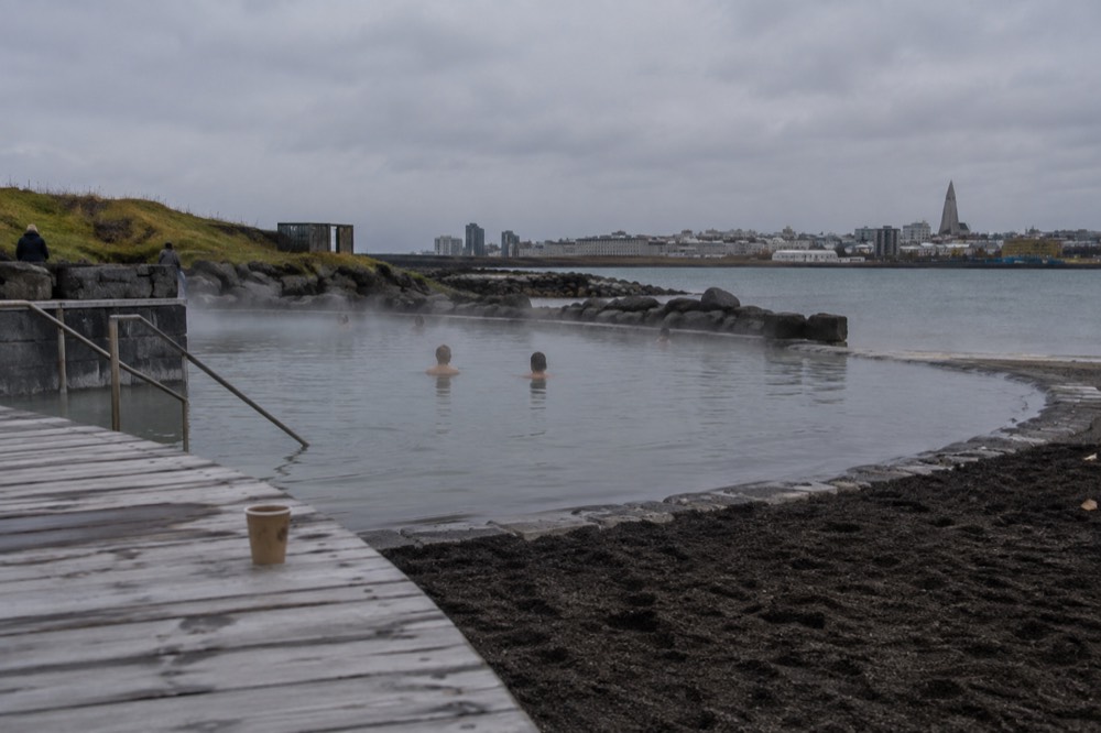 Geothermal steam rising over a small heated beach lagoon in Reykjavik
