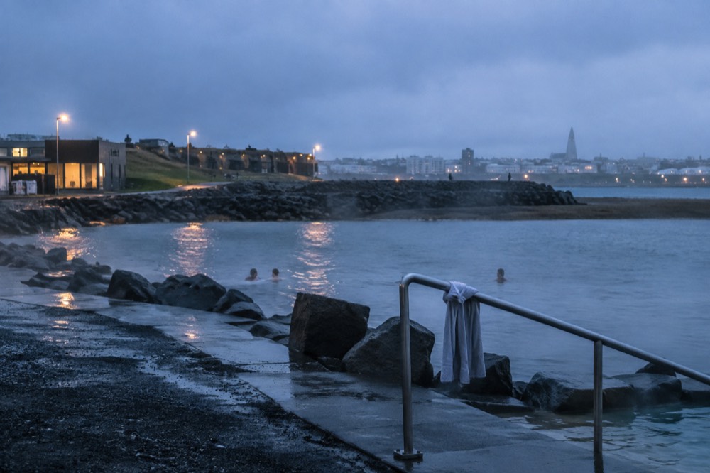 A steaming geothermal lagoon beside a dark sand beach in Reykjavik