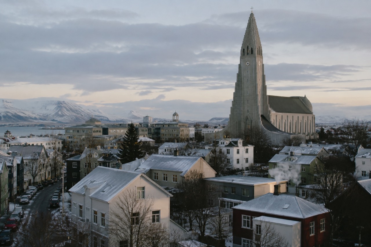 View across Reykjavik rooftops toward Hallgrimsurkirkja church under a wide sky