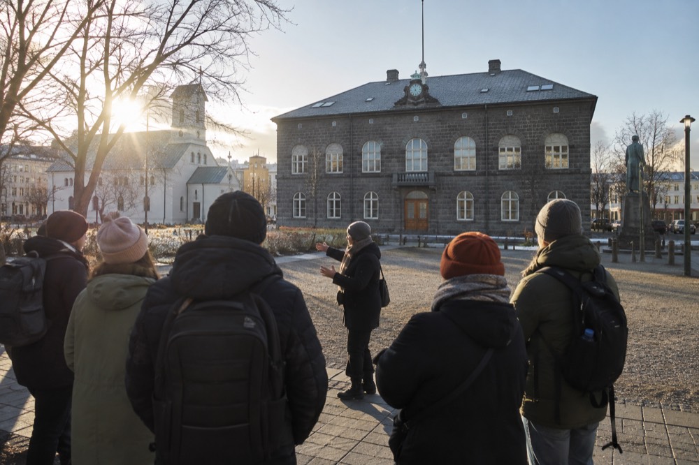 A guide speaking to a small group in a Reykjavik square beside old stone buildings