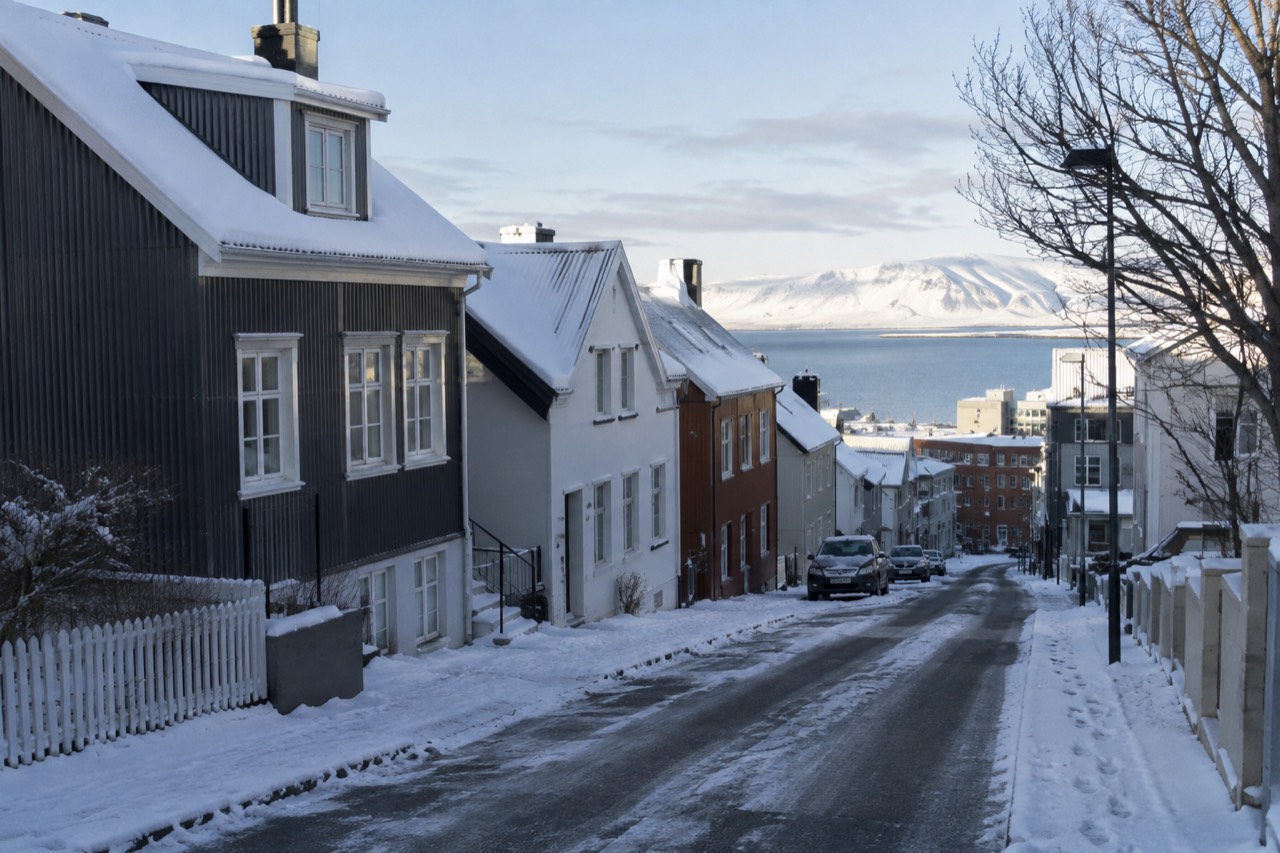 Snow covered rooftops and a quiet street in central Reykjavik under a pale winter sky