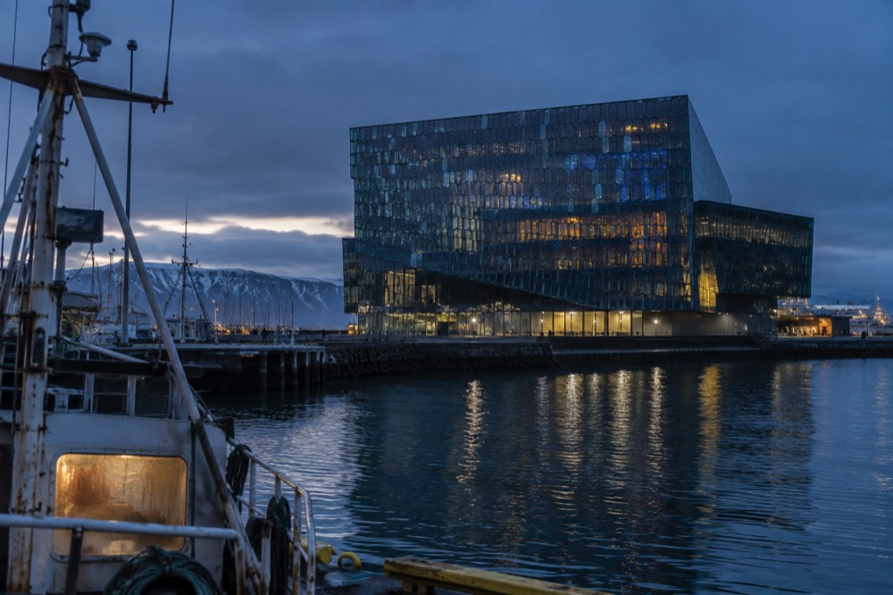 Harpa concert hall's glass facade reflecting the sky and harbor