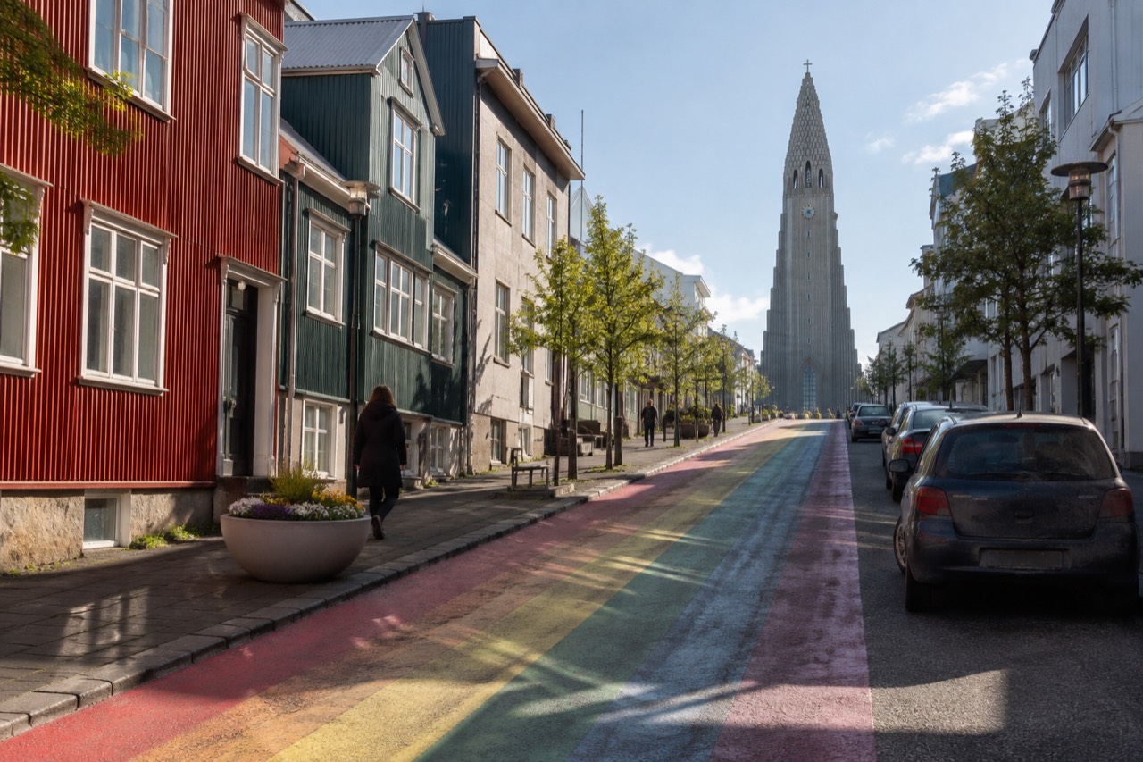 Colorful houses along a Reykjavík street with Hallgrímskirkja visible in the distance under a bright sky