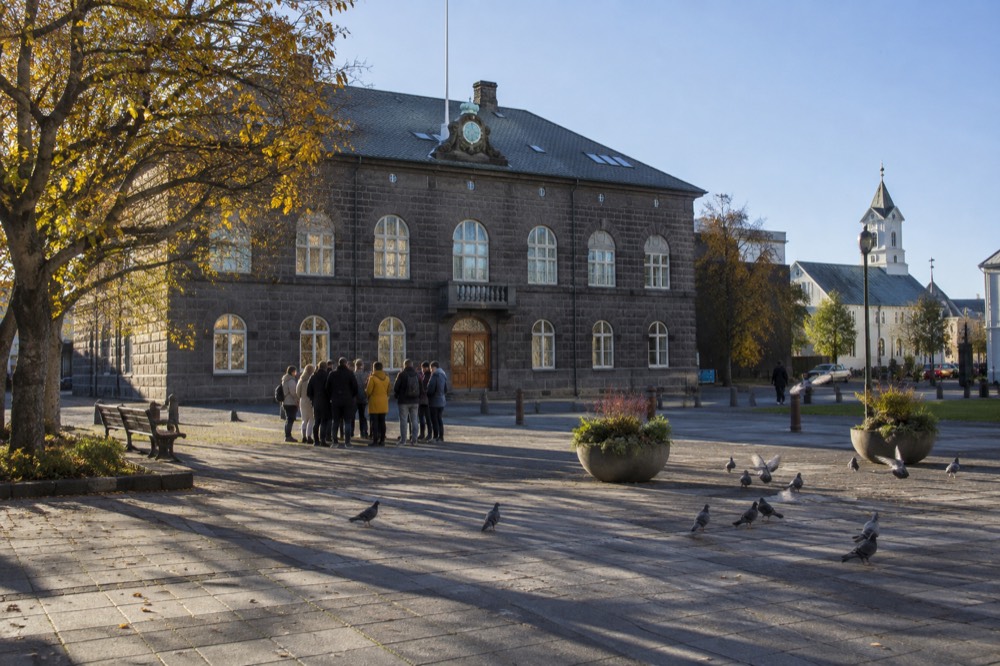 A guide with a small group standing in a Reykjavik square near the Parliament building