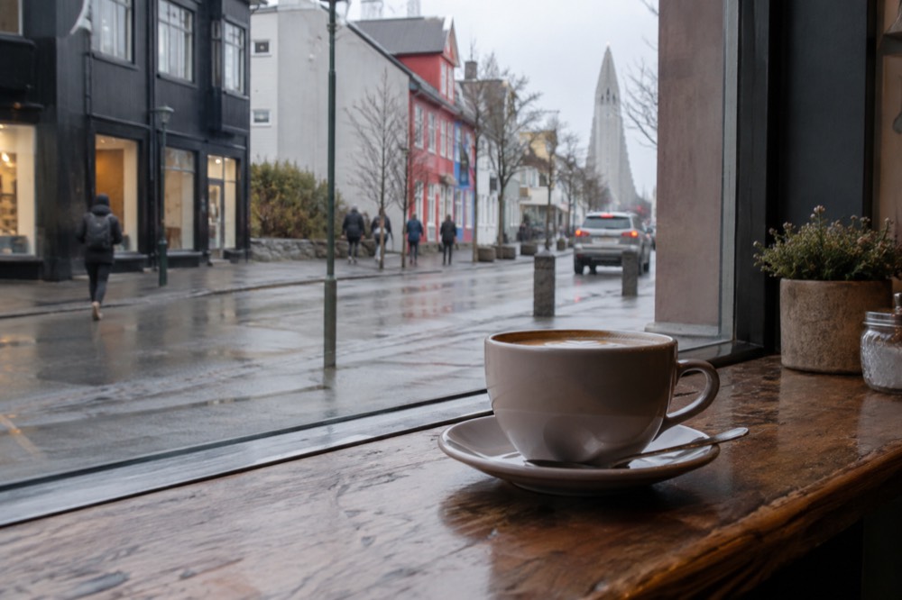 A coffee cup on a wooden counter beside a window in a Reykjavik café