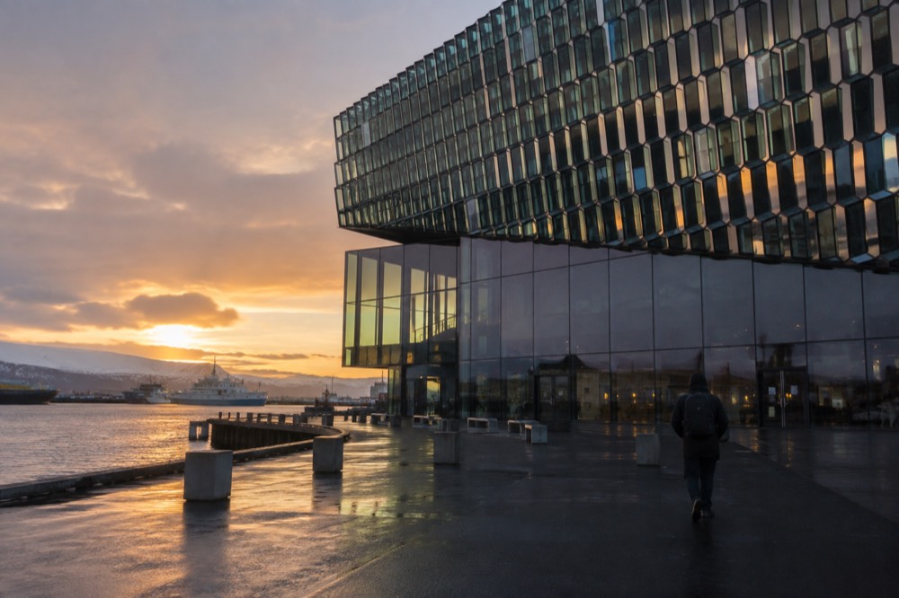 The glass facade of the Harpa concert hall reflecting evening light over the Reykjavik harbor