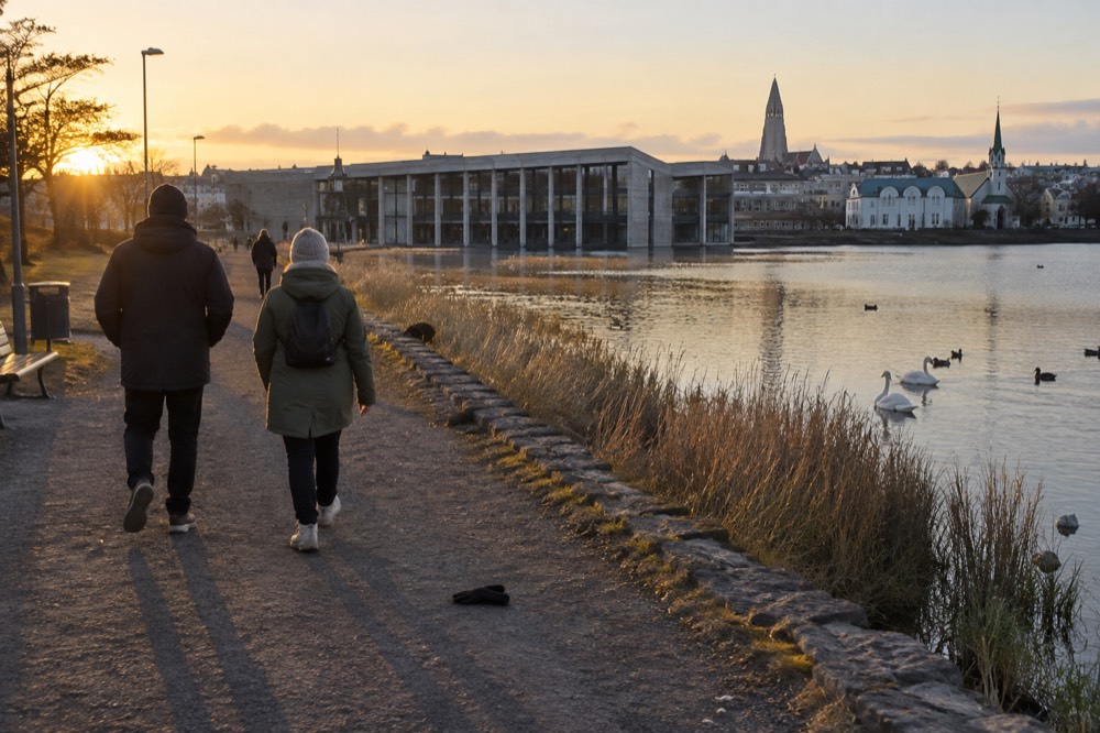 Pedestrians walking a paved path beside Lake Tjörnin toward the city center