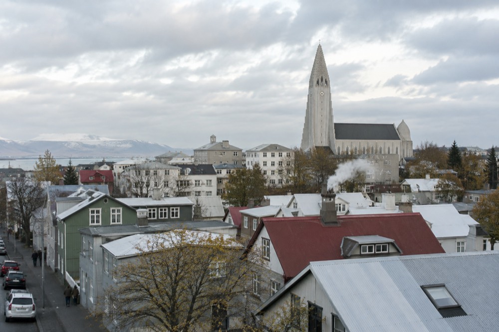 View across Reykjavik rooftops toward Hallgrímskirkja under a bright sky