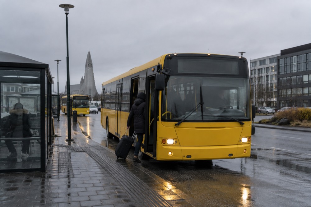 Bus waiting at a terminal curb under an overcast sky