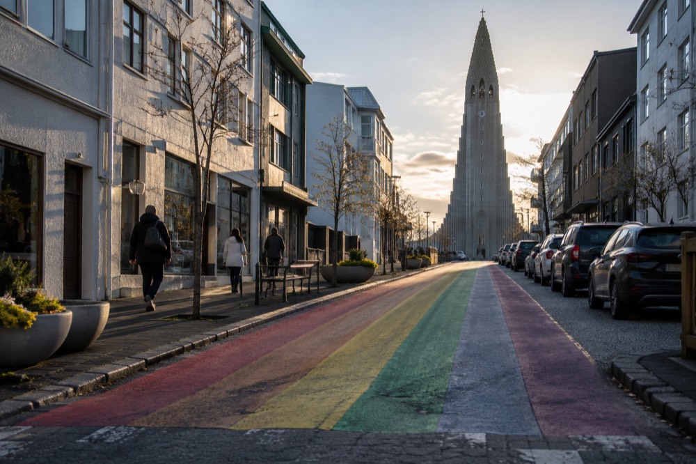 Rainbow painted street sloping down from a large stone church
