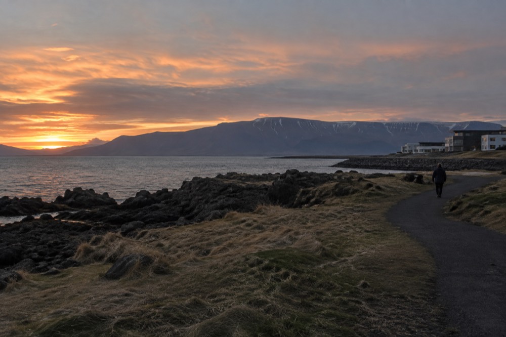 Coastal path at dusk with distant mountain ridge across the water