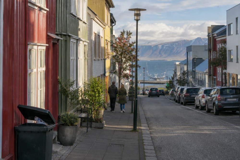 Colorful houses along a Reykjavik street in bright summer light with the Sun Voyager sculpture visible near the waterfront