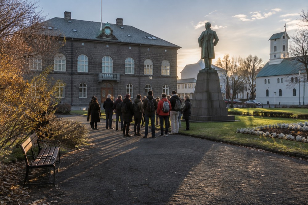 A guide with a small group standing in a Reykjavik square beside a statue