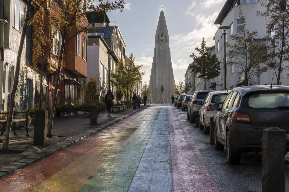 Rainbow-painted street rising toward a large stone church tower