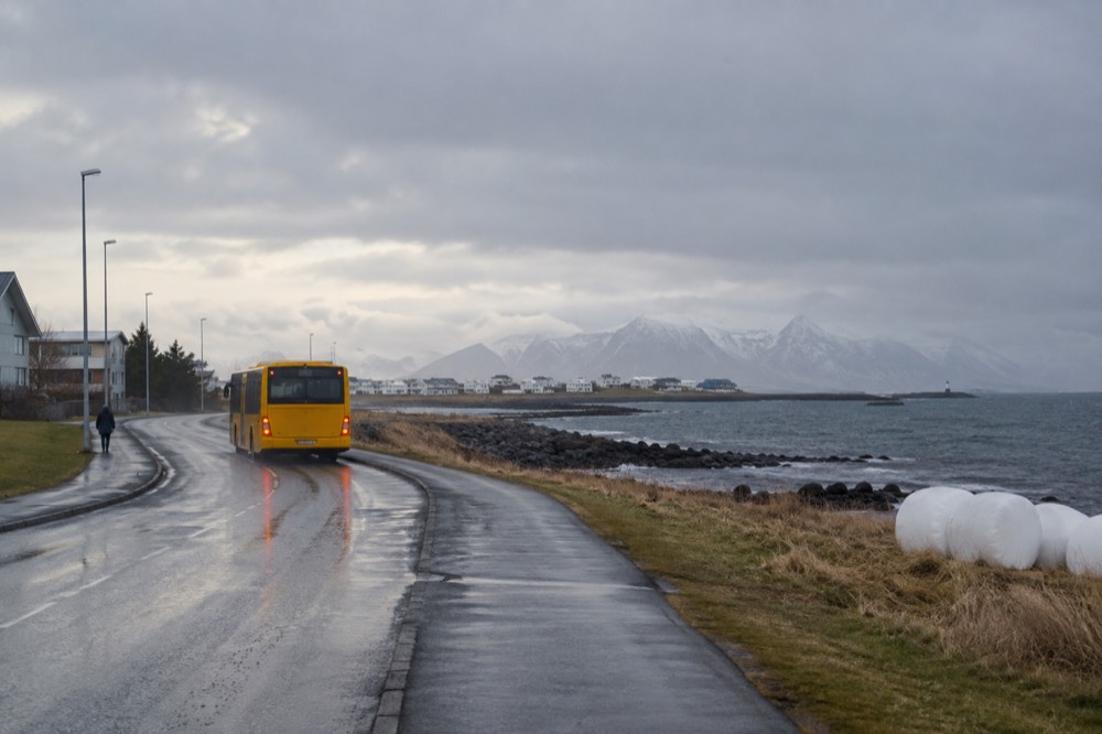 A city bus on a quiet coastal road with the sea on one side