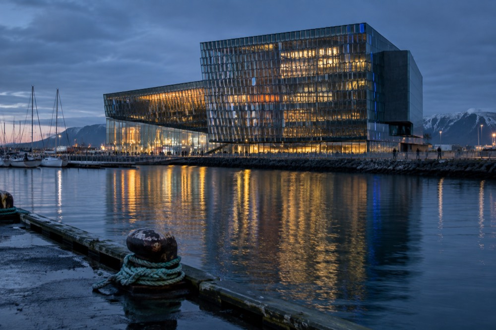 Harpa Concert Hall at dusk with the glass facade lit from inside, reflecting on the harbour water