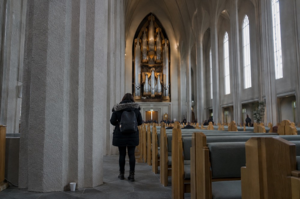 The interior of a large modern church with tall columns and an organ loft