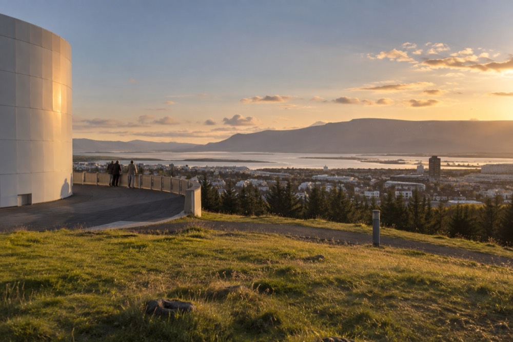 Panoramic view over Reykjavik rooftops and the bay seen from open ground beside the Perlan building