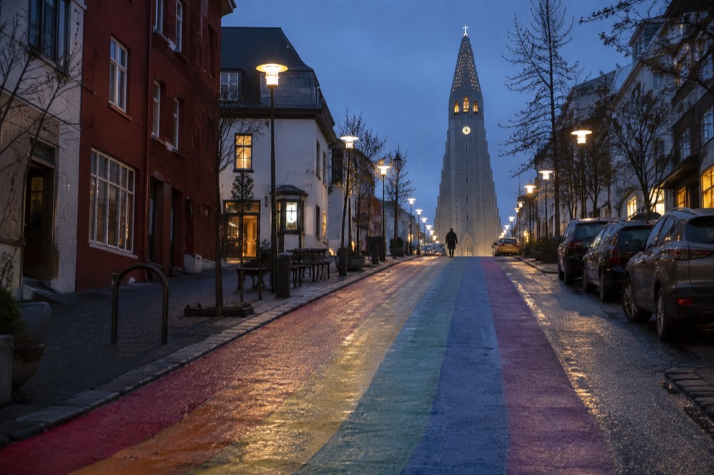 Rainbow painted street rising toward a large stone church in Reykjavik