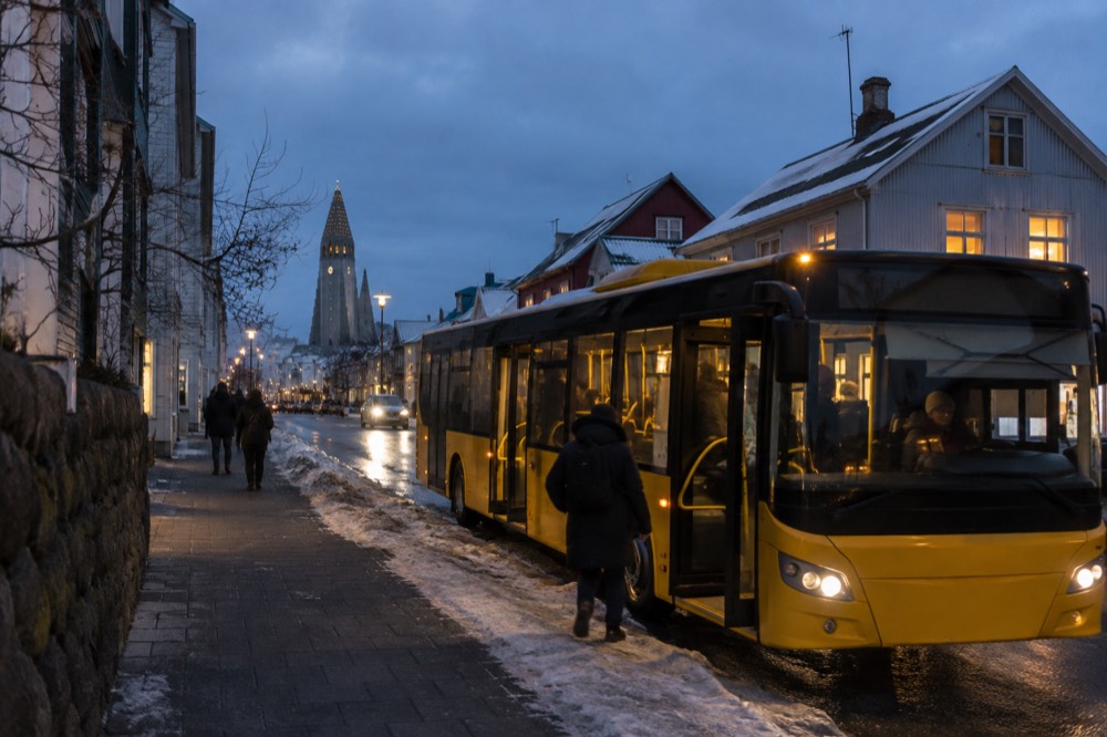 City bus at a stop on a Reykjavik street with low buildings behind