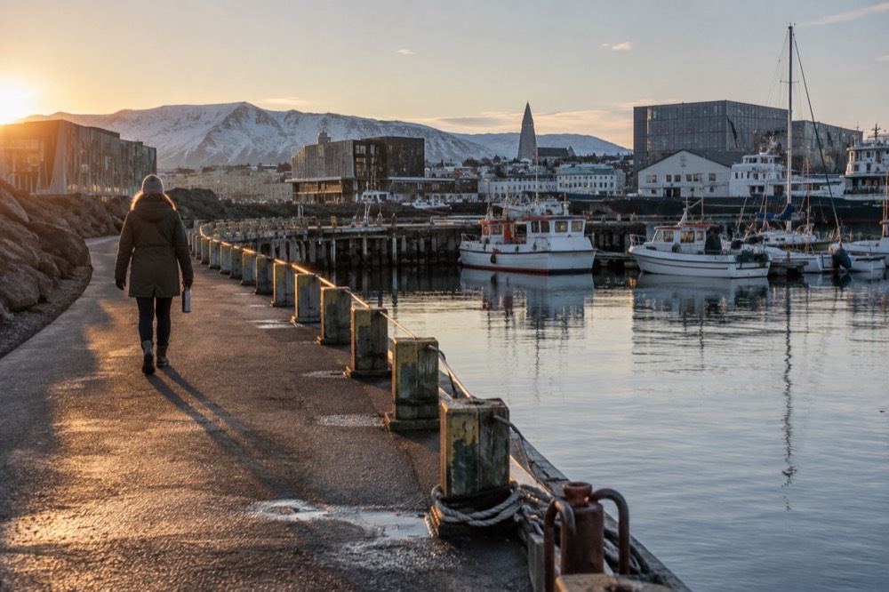 The paved waterfront path curving along the harbour with small boats at anchor