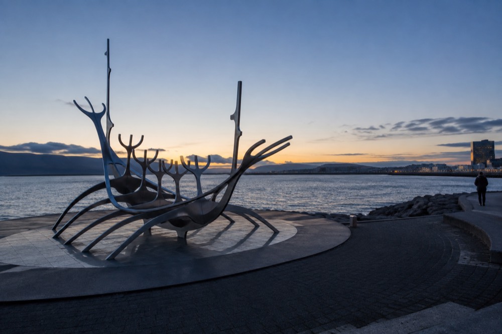 A steel boat sculpture silhouetted on the waterfront with open water behind it