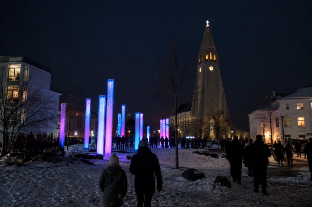 Colorful light installations glowing on a dark winter street in Reykjavik with snow on the ground
