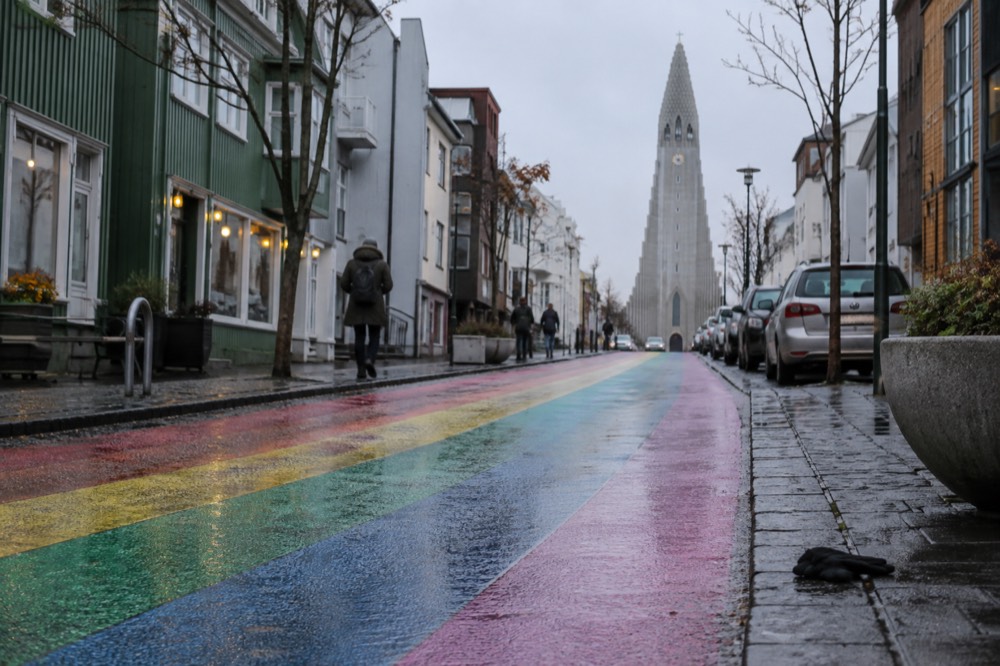 A painted rainbow street rising toward a large stone church