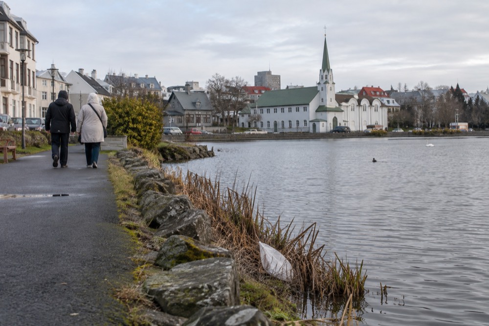 Pedestrian path along the Tjörnin shoreline leading toward the old town and harbour