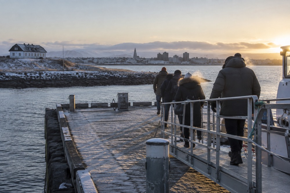 Passengers walking down a ferry gangplank onto a quiet island pier