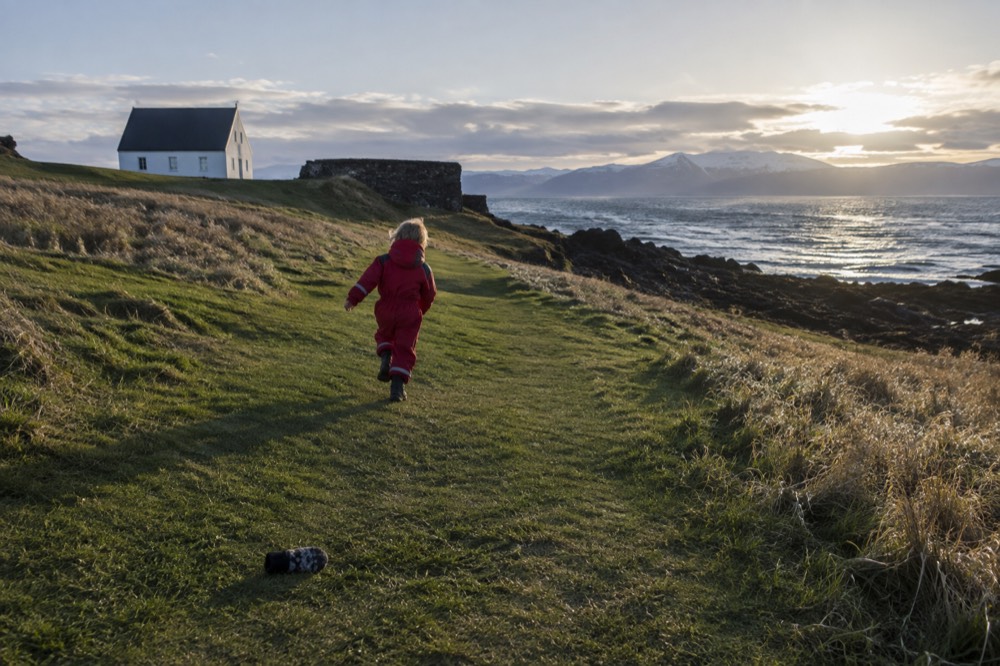 A child running along a grassy island path with the sea in the background