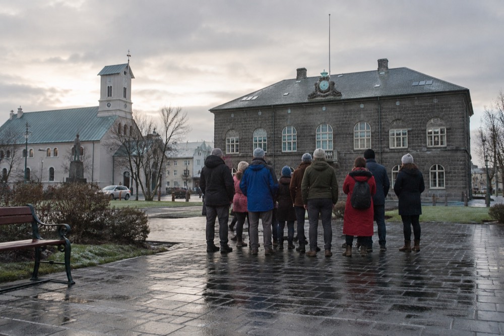 A tour guide speaking to a small group on a city square near the harbor